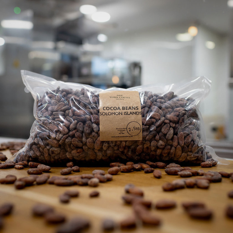 Bag of cocoa beans from Solomon Islands on a wooden surface with blurred factory  background