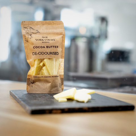 Packaged cocoa butter on a slate surface with blurred factory background