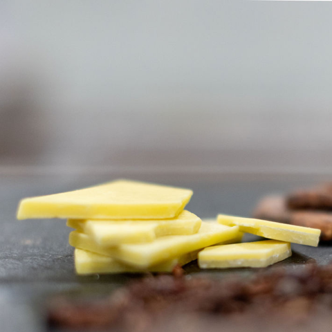 Close up of a stack of cocoa butter pieces on a slate surface with a blurred background