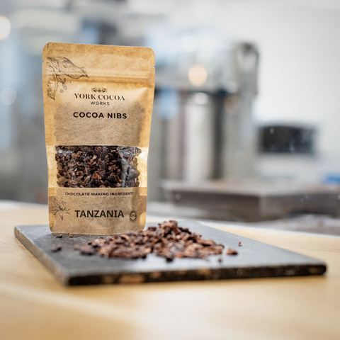 Package of York Cocoa Works Ecuador cocoa nibs on a slate surface and a blurred factory background