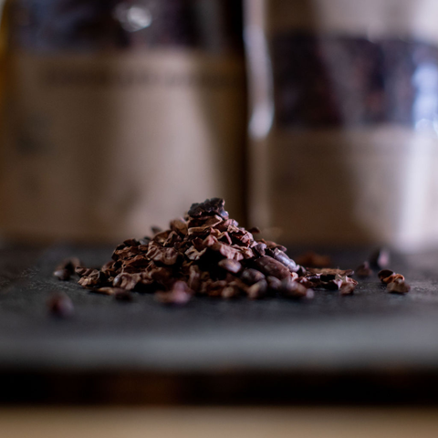 Pile of cocoa nibs with blurred packets in  the background