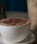 Milk Hot Chocolate topped with chocolate flakes and a packet in the background.